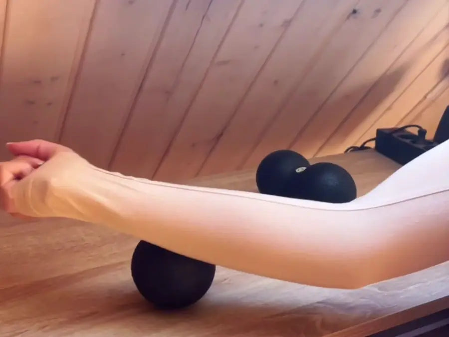 Selbstmassage des Unterarms mit einem Massageball auf dem Tisch